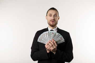 Portrait of surprised handsome businessman wearing black suit showing money banknotes