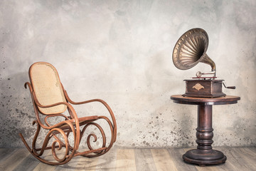 Vintage antique gramophone phonograph turntable with brass horn on wooden table and aged rocking...