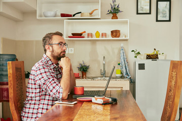 Modern bearded man using cellphone and drinking coffee with laptop.