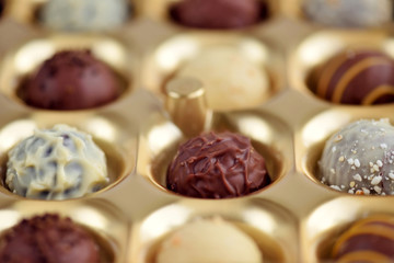 Assorted of chocolate candies in gold gift box. Selective focus