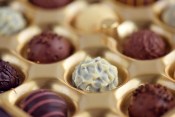 Assorted of chocolate candies in gold gift box. Selective focus