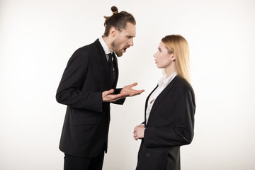 Attractive businessman with beard and trendy hairstyle in black suit screaming at his subordinate who can't cope the task