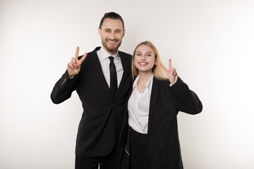 Two employees laugh happily at the end of the working week, showing viktory sign and looking at the camera