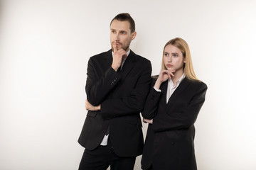 Two business partners in black suits, handsome bearded man and beautiful blonde woman thinking about solving the probleme at work