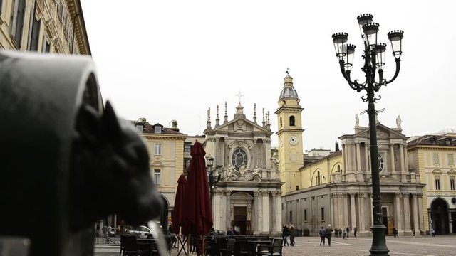 Turin, Piedmont, Italy. April 2019. A look at Piazza San Carlo. On the left in the foreground the fountain with the green bull, called turet, on the right the two twin churches. People are walking.