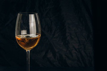 cropped glass of white wine on a black background. rest, holiday, party. isolated alcoholic drink closeup.
