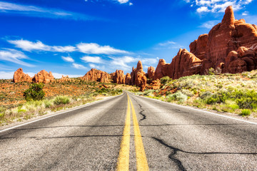 Rijden door de woestijn met Monument Rock langs de weg tijdens zonnige dag, Arches NP
