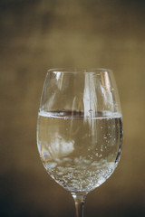 cropped glass of white wine on a rustic wooden brown background. rest, holiday, party. alcoholic drink closeup. copy space