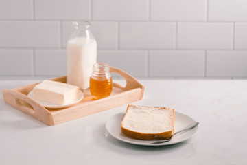 Breakfast table with bread slice, butter, milk and honey