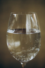 cropped glass of white wine on a rustic wooden brown background. rest, holiday, party. alcoholic drink closeup. copy space