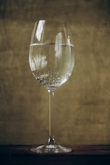 cropped glass of white wine on a rustic wooden brown background. rest, holiday, party. alcoholic drink closeup. copy space