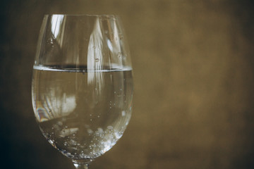 cropped glass of white wine on a rustic wooden brown background. rest, holiday, party. alcoholic drink closeup. copy space