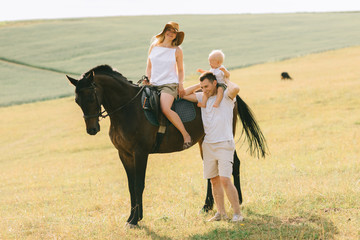 A young family have a fun in the field. Parents and child with a horse