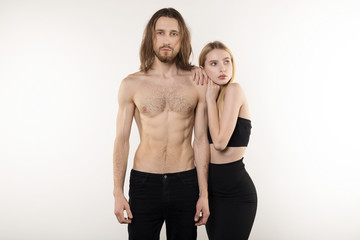 Young serious beautiful woman in black skirt and man in black jeans and with naked torso