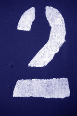 Number 2 in stencil on metal wall in blue tone.