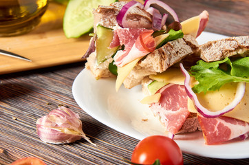 Sandwich with bacon, cheese, garlic, jalapeno pepper and herbs on a plate