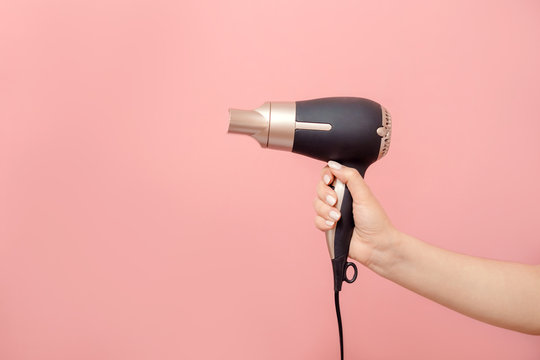 In Hand Of Woman Hair Dryer On Pink Background