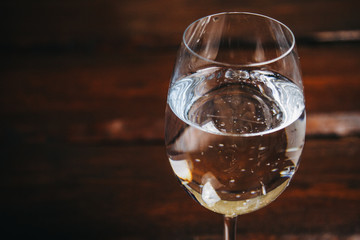 cropped glass of white wine on a rustic wooden brown background. rest, holiday, party. alcoholic drink closeup. copy space