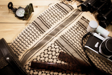 Camera film compass with shemagh scarf on wooden table. travel equipment. copy space. retro style.