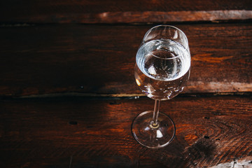 A glass of white wine on a rustic wooden red background. rest, holiday, party. crystal glass closeup. copy space. top view