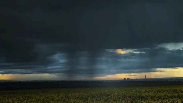 Time lapse of large storm clouds passing on a summers day with torrential down pours over farm crops