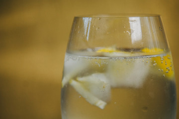 A glass of homemade lemonade with ice and lime on a rustic wooden brown background. rest, holiday, party. crystal glass closeup. copy space