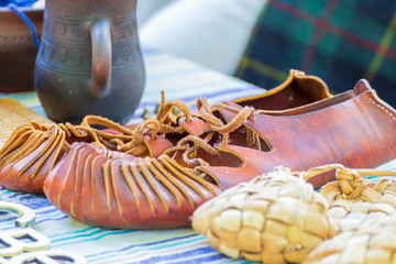 Wicker and leather bast shoes on a rustic homespun walkway.