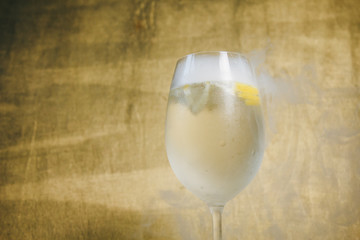 A glass of homemade lemonade with ice and lime on a rustic wooden brown background. rest, holiday, party. crystal glass closeup. copy space