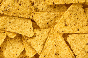 The background of yellow triangular corn nachos close-up