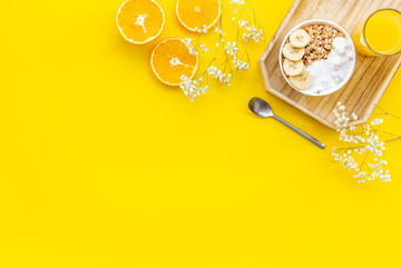 Healthy granola with banana and orange juice for colorful breakfast on yellow background top view mock-up