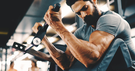 Muscular bodybuilder guy doing exercises in gym