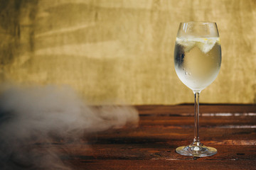 A glass of homemade lemonade with ice and lime on a rustic wooden brown background. rest, holiday, party. crystal glass closeup. copy space