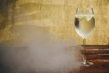 A glass of homemade lemonade with ice and lime on a rustic wooden brown background. rest, holiday, party. crystal glass closeup. copy space