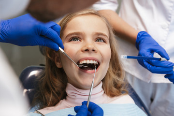 Happy beautiful child girl sitting in medical dentist center.