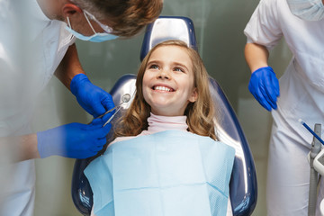 Happy beautiful child girl sitting in medical dentist center.