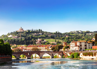 Fototapeta premium View of Verona with Ponte Pietra bridge over the Adige river and the Sanctuary of our lady of Lourdes on a hill, Italy