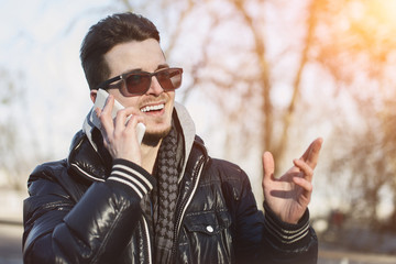 Caucasian Man on the street, talking on the phone with a smile on the street.