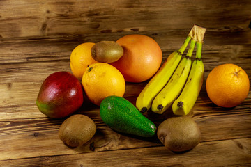 Assortment of tropical fruits on wooden table. Still life with bananas, mango, oranges, avocado, grapefruit and kiwi fruits