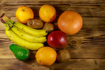 Assortment of tropical fruits on wooden table. Still life with bananas, mango, oranges, avocado, grapefruit and kiwi fruits