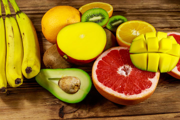 Naklejka na ściany i meble Assortment of tropical fruits on wooden table. Still life with bananas, mango, oranges, avocado, grapefruit and kiwi fruits