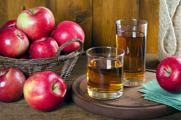 Apple juice in glasses and red apples in a basket.