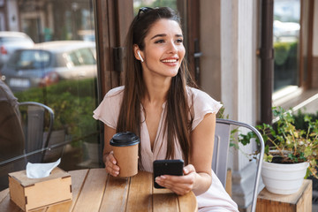 Smiling pretty woman sitting at the cafe outdoors