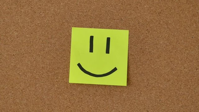 Close-up of the person sticking notes whith smiles on the board. Sad and Happy smiles on stickers.
