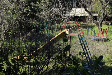 swings and slides in abandoned overgrown playground