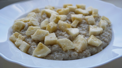 OATED POTENTA IN A PLATE WITH APPLES SALES AND A BANANA WHITE BACKGROUND
