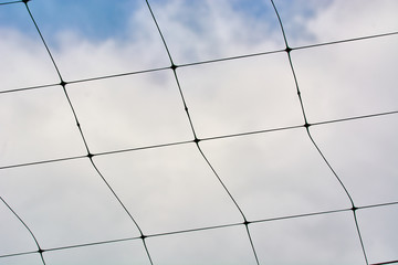 Beautiful volleyball net against the blue sky with clouds.