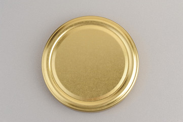 Screw cap for glass jars. For canning, canned food. Golden cap on gray background