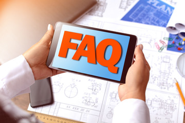 A girl (architect, student, businesswoman) at a table with business accessories, accessories for drawing (plans, rulers) and training with tablet with text FAQ