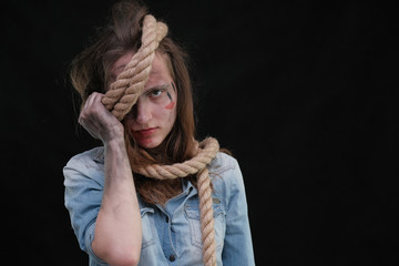Concept portrait of offended, displeased, dirty, sharpened in captivity brunette girl on a black background, bound by a rope. Violence against women.