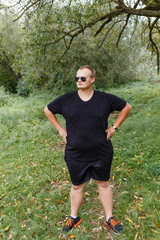 serious fat guy in sunglasses in the forest